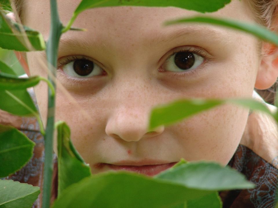 student peeking through leaves