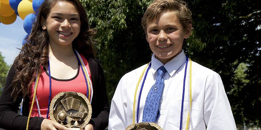 students holding academic award trophies
