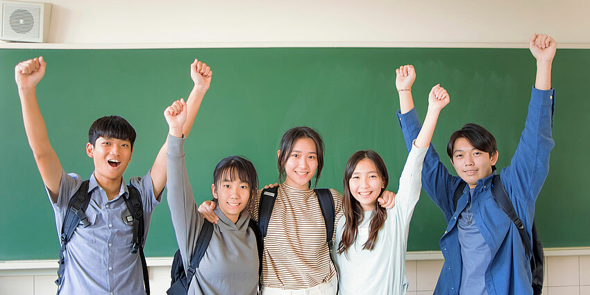 students standing side by side with their arms up in the air