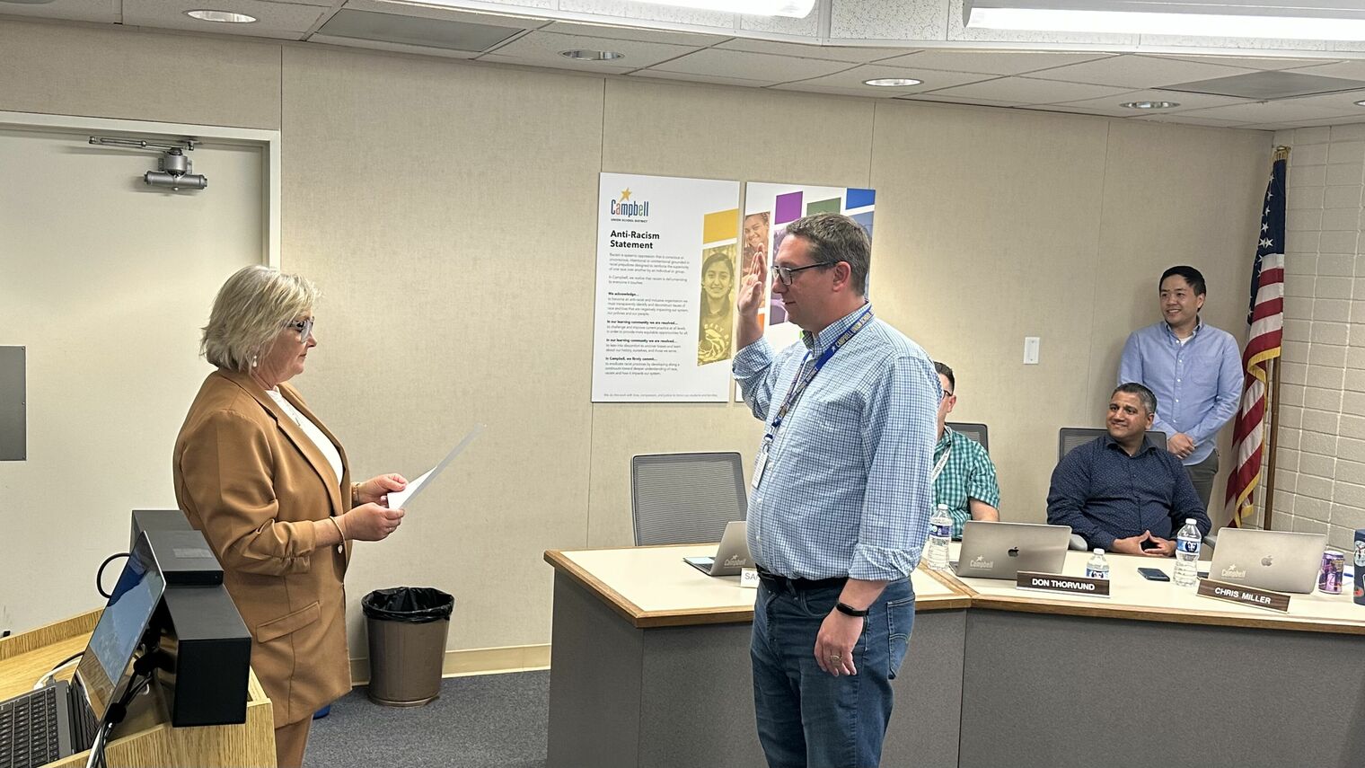 Area 5 trustee Sam Krow-Lucal is taking the oath of office. The oath is presented by Superintendent Viramontez and fellow board members are looking on.