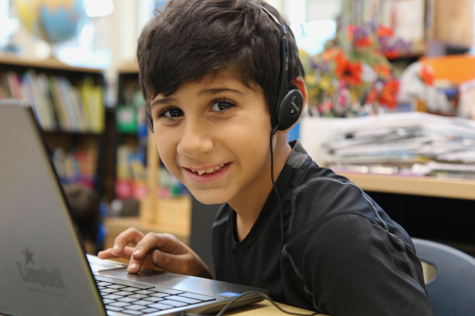 smiling boy with laptop and wearing headphones