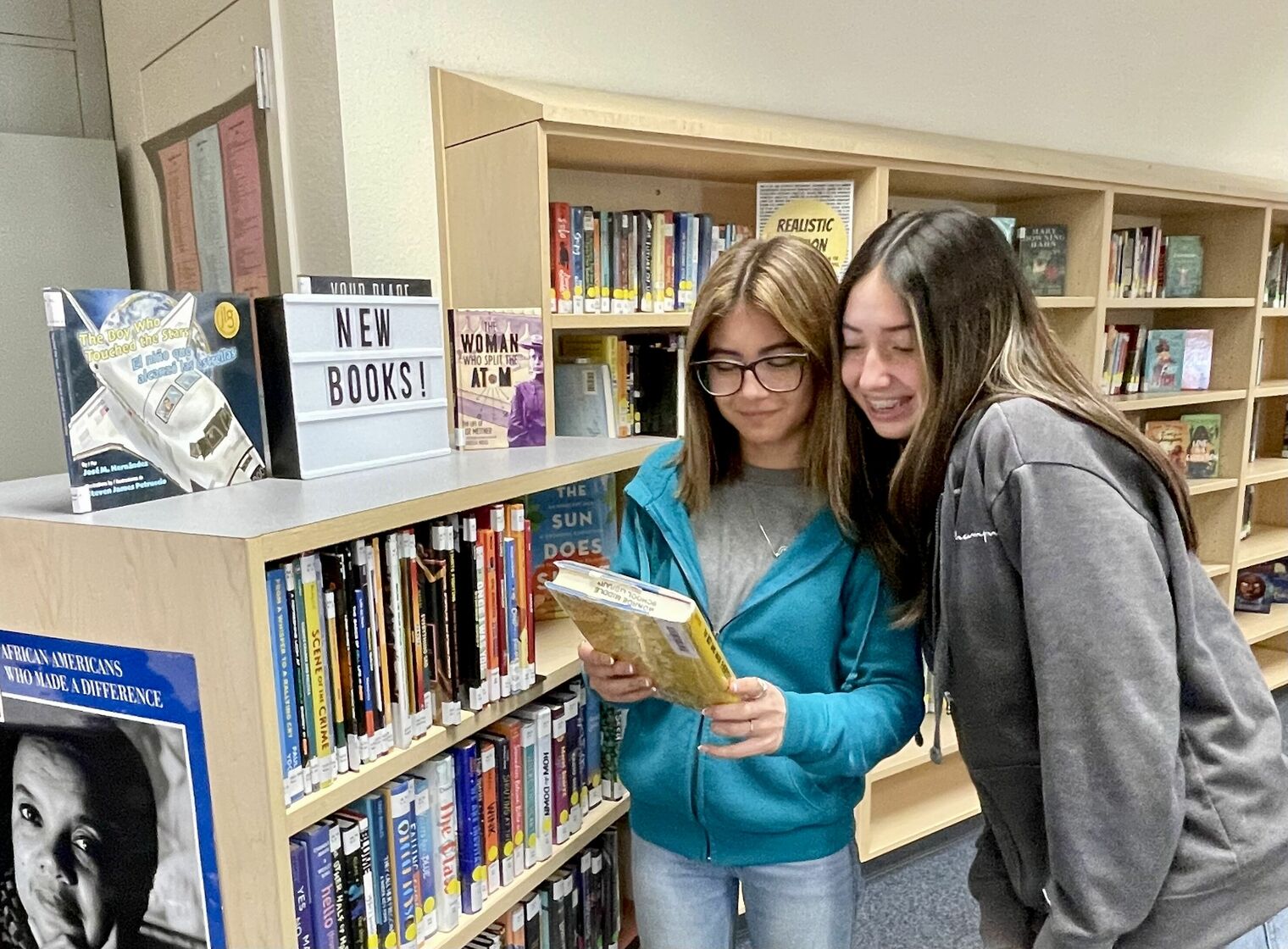 two female students in the library looking at book together