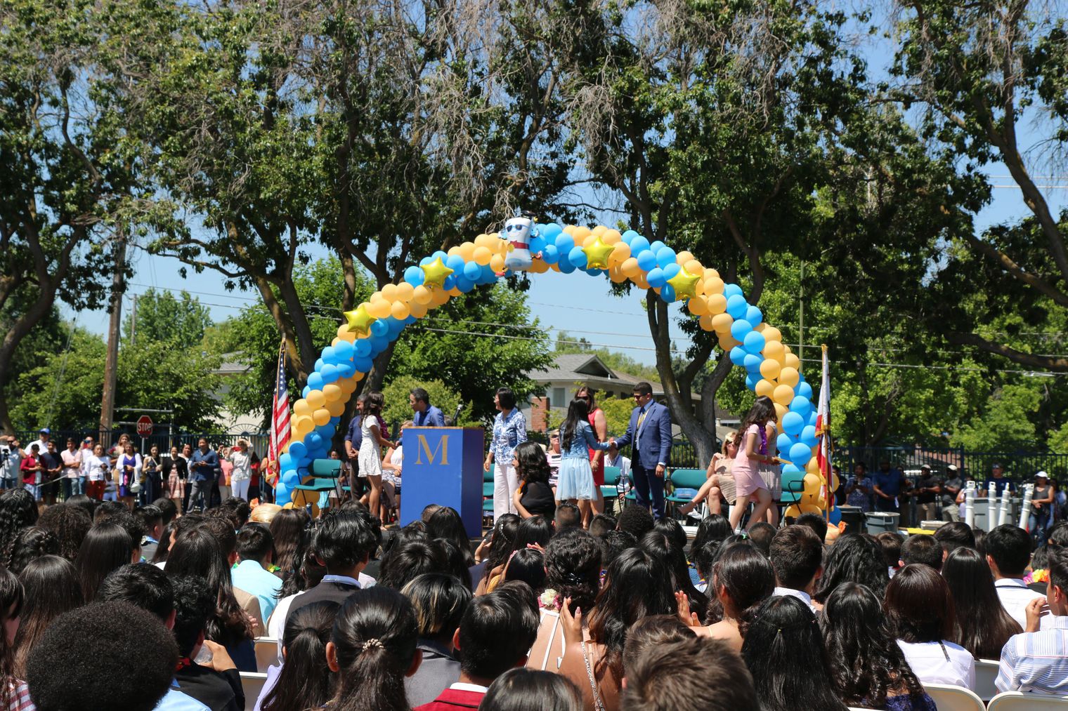 Arch of balloons above the stage where students are crossing for a promotional ceremony 
