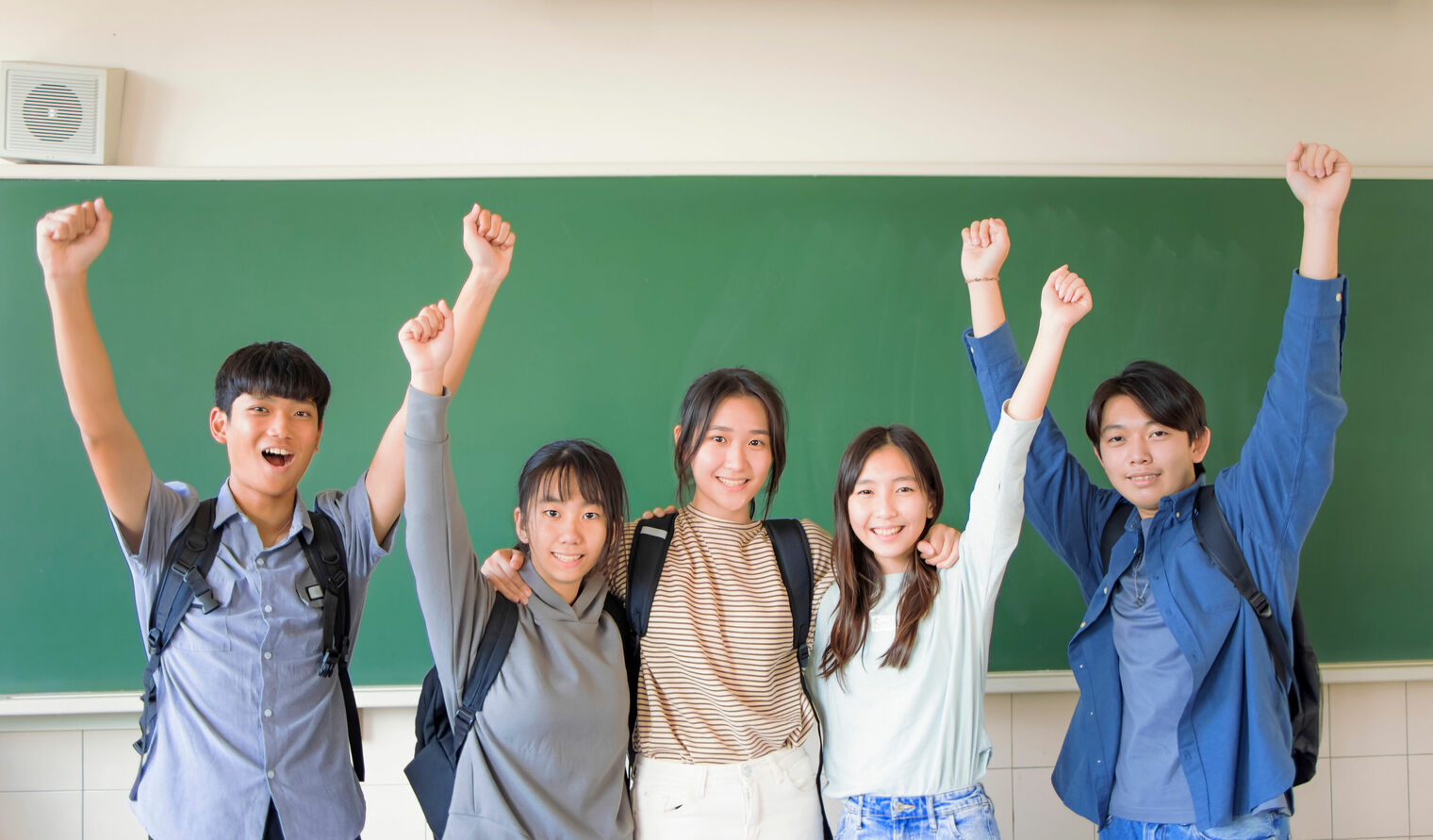 students standing side by side with their arms up in the air